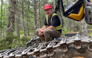 Man sitting on piece of forestry equipment in woods